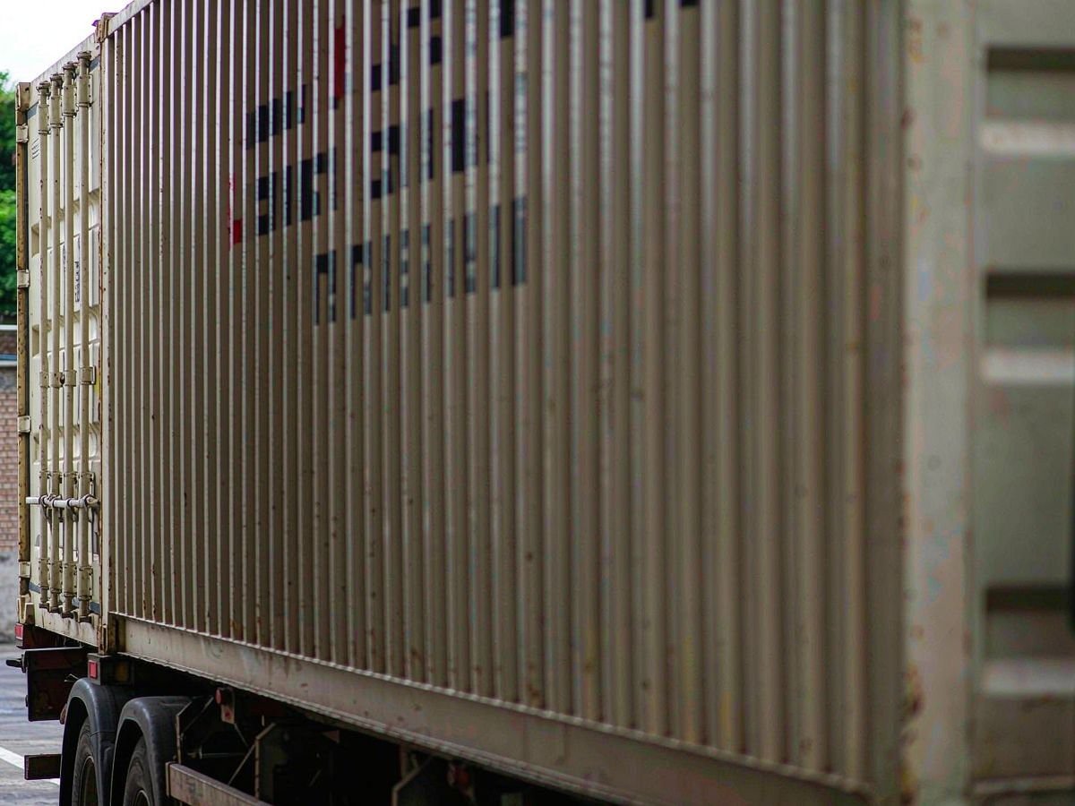 Sealed shipping container on a truck trailer leaving a factory gate