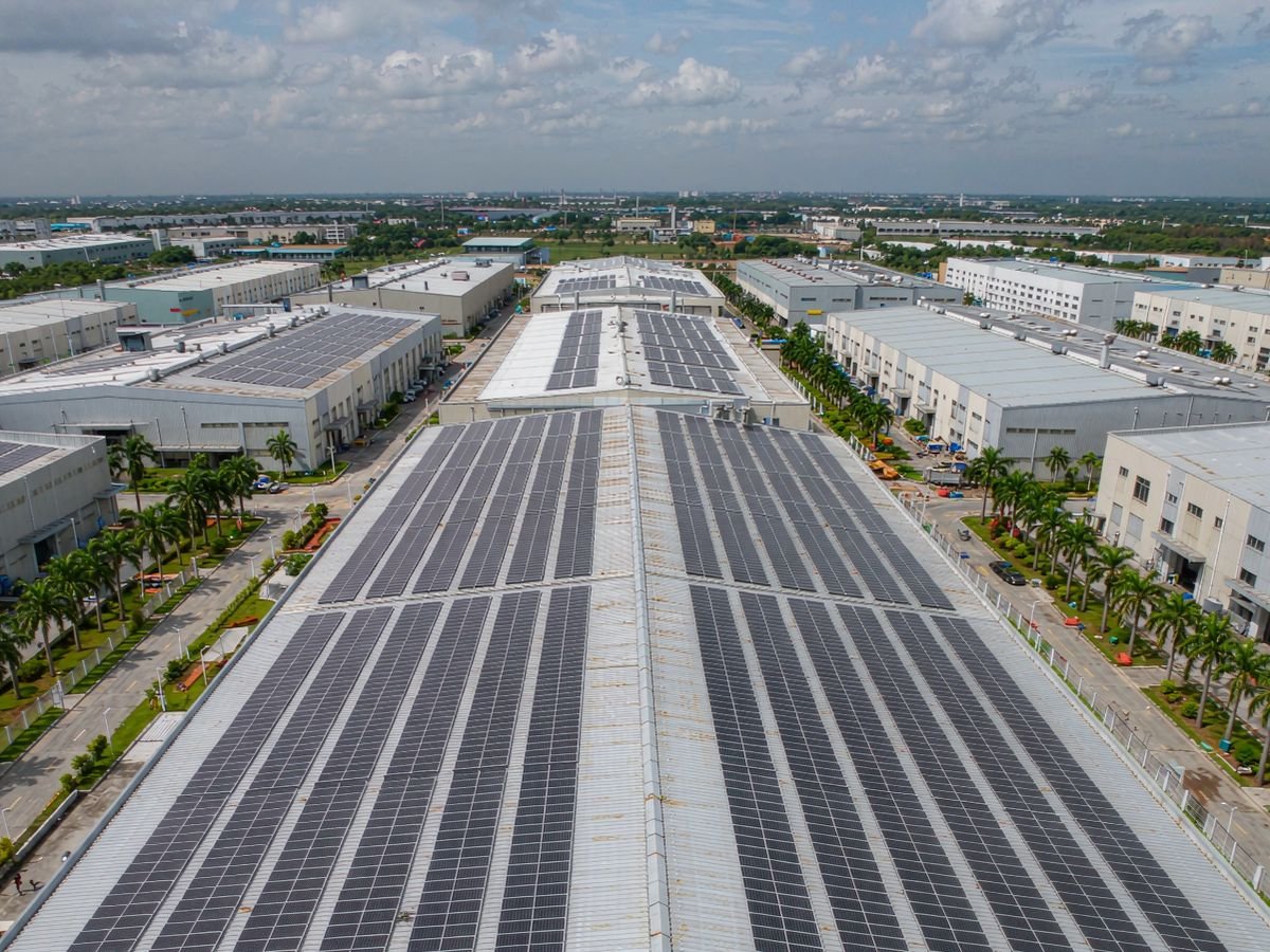 Solar power system price in the Philippines: aerial view of a warehouse rooftop array on corrugated metal roofing in a tropical industrial park